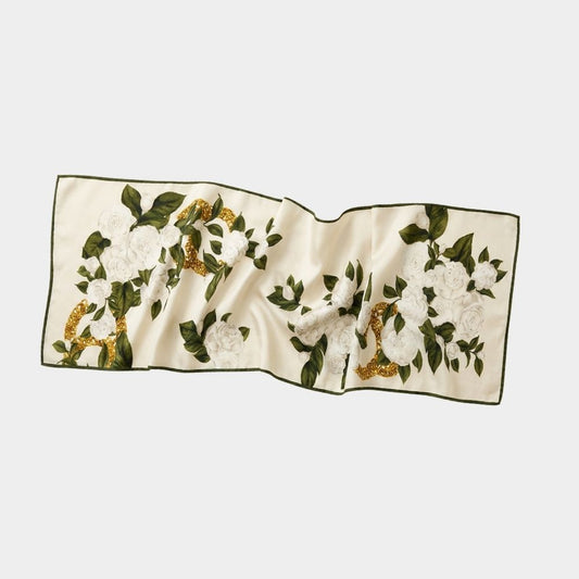 Flat lay of Camellia mulberry silk scarf with white camellia flowers, soft green leaves, and gold detailing