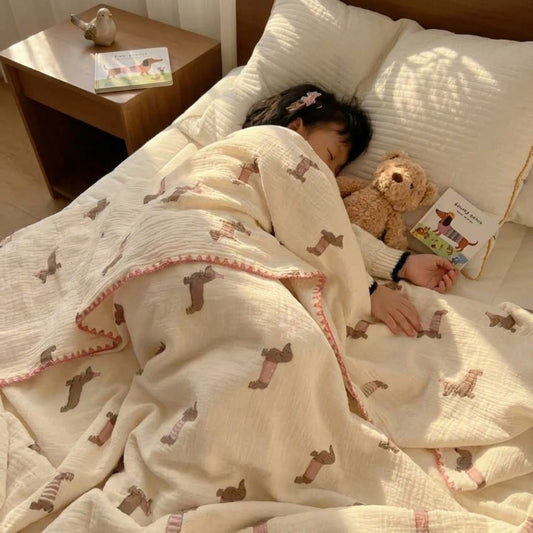 Cloud cotton muslin blanket in Pudding draped on bed — party dachshund print, MonBebe Singapore