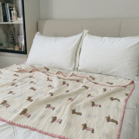 Cloud cotton muslin blanket in Pudding draped on bed — party dachshund print, MonBebe Singapore