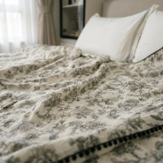 Cloud cotton muslin blanket in Secret Garden draped on bed — black botanical print, MonBebe Singapore