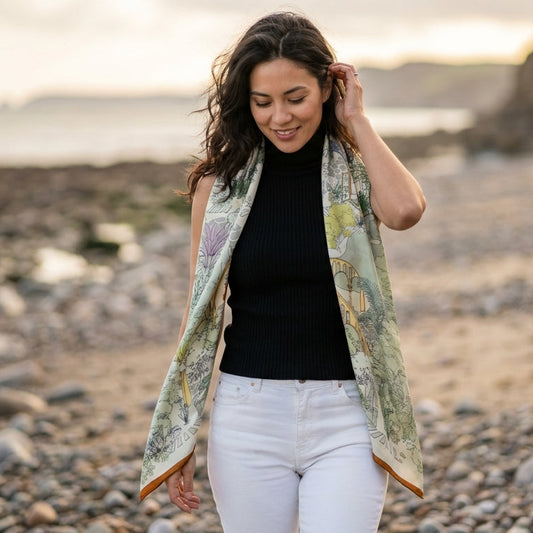 Silk-wool shawl worn over the shoulders, featuring a romantic illustrated botanical design in soft muted tones