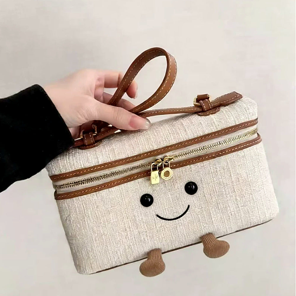 Laura Smiley crossbody bag in beige fabric material with gold zipper, tan leather handle, and corduroy feet up close shot