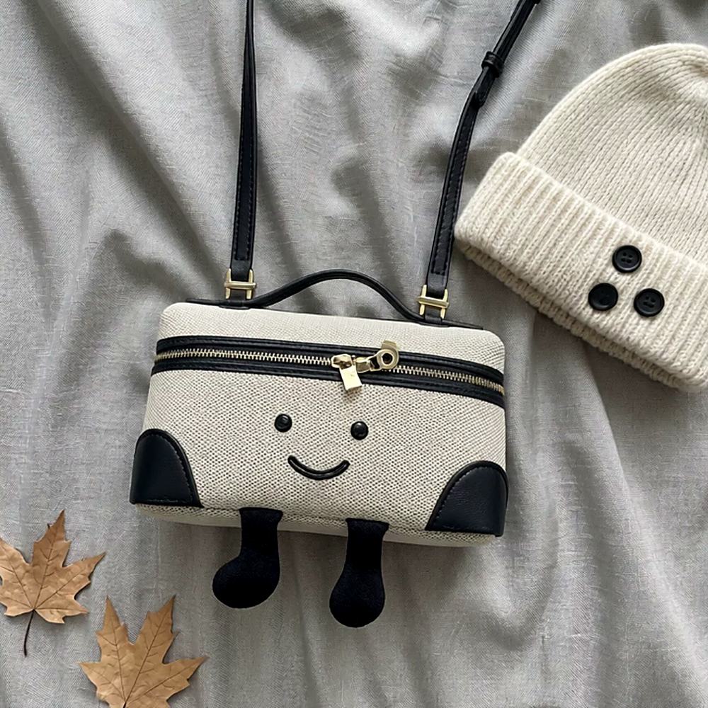 Laura Smiley crossbody bag in cream and black canvas material with gold zipper, black leather handle, black leather strap and corduroy feet