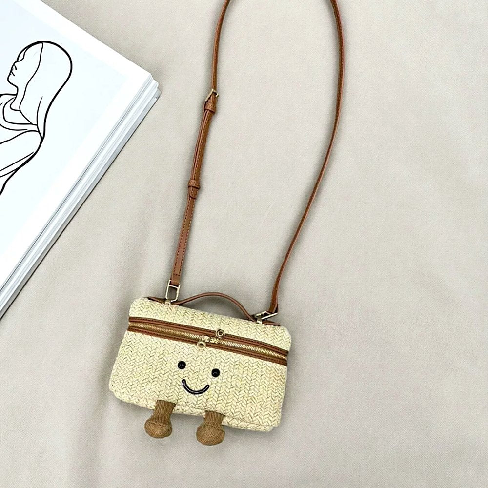 Laura Smiley crossbody bag in straw material with gold zipper, tan leather handle, tan leather strap, and corduroy feet