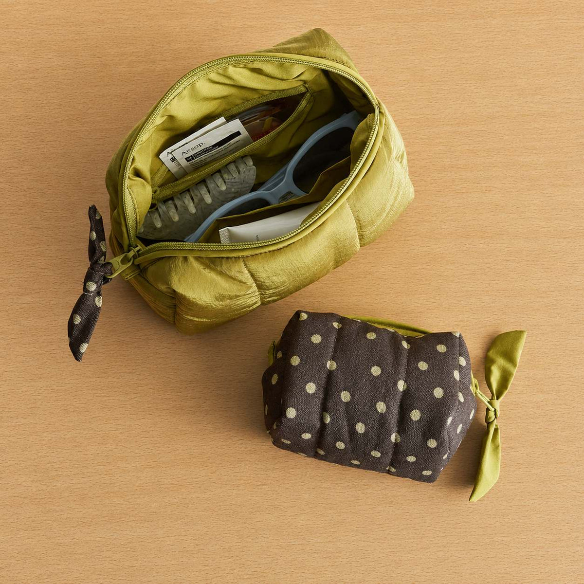 Open Poppy quilted travel case packed with sunglasses and hair clip beside a Small polka dot pouch, MonBebe Singapore