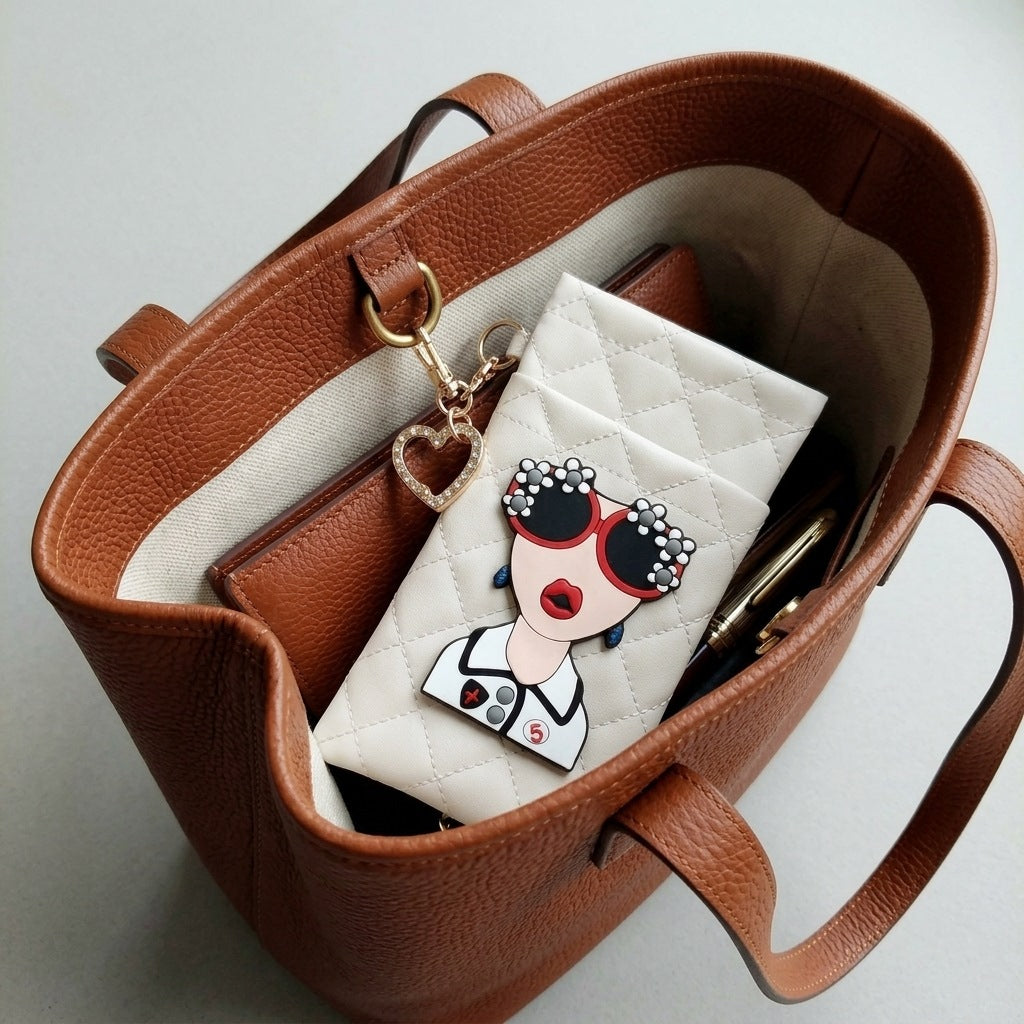 Cream glasses case with heart-shaped rhinestone hook clipped inside a tan tote bag